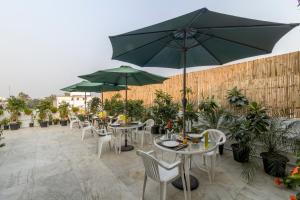 a patio with tables and chairs with umbrellas at Colonel's Retreat 2 in New Delhi