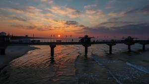 a bridge over the water with the sunset in the background at Kolorowe Balkony II by Renters in Międzyzdroje