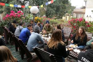 un grupo de personas sentadas alrededor de una mesa comiendo comida en Shangri-la Boutique Hotel, en Katmandú