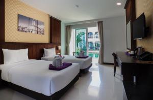 una camera d'albergo con due letti e una televisione di Supicha Pool Access Hotel - SHA Plus a Phuket