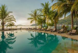 a swimming pool with chaise lounge chairs and palm trees at Swiss-Belhotel Papua in Jayapura