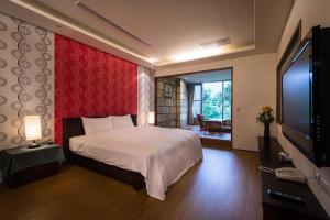 a bedroom with a bed and a flat screen tv at Wulai SungLyu Hot Spring Resort in Wulai