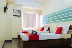 two beds in a hotel room with red pillows at RedDoorz @ MJ Cuenco Avenue Cebu in Cebu City