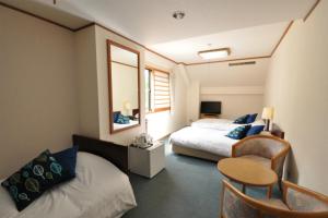 a bedroom with two beds and a table and a chair at Hakuba Yamano Hotel in Hakuba