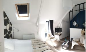een witte slaapkamer met een bed en een stoel bij Patis De Cahot au 108 in Bruz