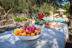 eine Schale mit Obst und Gemüse auf einem Tisch neben einem Pool in der Unterkunft Mastrogiannis villa Dafne in Kavvadádes