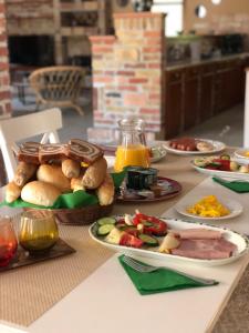a table topped with plates of food and orange juice at Woodland Villa in Gyula
