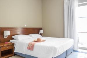 a bedroom with a bed with a hat on it at Neptuno Beach Hotel in Amoudara Herakliou