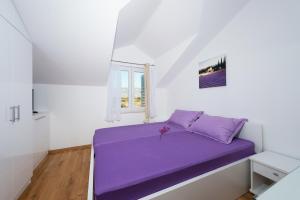 a purple bed in a white room with a window at Villa Stani, luxury villa with a pool in Novalja +40 photos