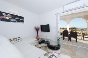 ein Wohnzimmer mit einem weißen Sofa und einem Glastisch in der Unterkunft Villa Stani, luxury villa with a pool in Novalja