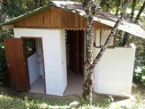 a toilet in a shed next to a tree at Gran Camping Cabanas da Fazenda in Visconde De Maua