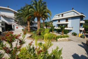 un complexe avec des palmiers et un bâtiment dans l'établissement Villaggio Verde Cupra, à Cupra Marittima