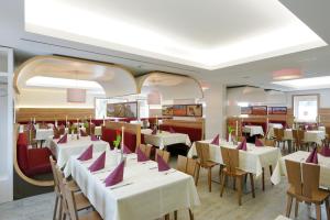 a restaurant with white tables and chairs with purple napkins at Hotel zur Post in Leipheim