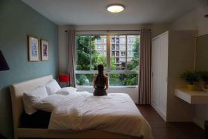 a woman sitting on a bed in front of a window at Baan Thew Lom Condo Cha am By PoPu in Ban Sahakham +26 photos