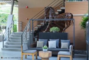 a patio with a couch and two chairs and stairs at Baan Thew Lom Condo Cha am By PoPu in Ban Sahakham