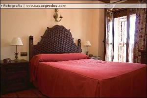 um quarto com uma cama vermelha e uma colcha vermelha em Casa Rural Las Eras de Riofrio em Ríofrío