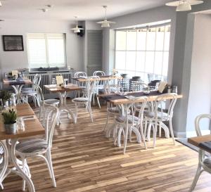 a restaurant with wooden tables and white chairs at The Beach House in West Wittering