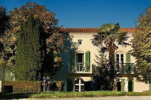 una casa grande con una palmera delante de ella en Appartement 91 Palais des Gouverneurs en Saint-Martin-de-Ré