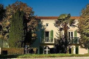 a large house with a palm tree in front of it at Appartement 91 Palais des Gouverneurs in Saint-Martin-de-Ré