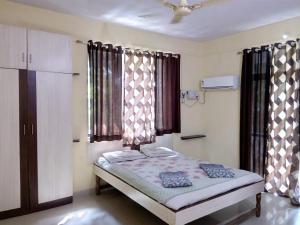 a bedroom with a bed and two windows at Tendulkar Beach Resort in Diveagar