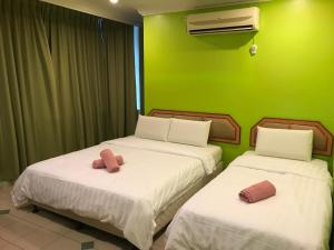 2 łóżka w pokoju z zieloną ścianą w obiekcie Hotel dan Restoran Seri Kangsar w mieście Kuala Kangsar