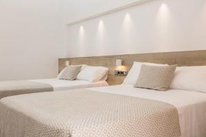 two beds in a room with white walls at RVHotels Nieves Mar in L'Escala