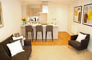 a living room with a couch and a kitchen at Portfolio Apartments - Welwyn Business Park in Welwyn Garden City