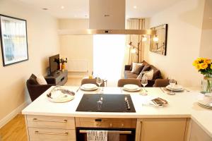 a kitchen with a stove top oven next to a living room at Portfolio Apartments - Welwyn Business Park in Welwyn Garden City