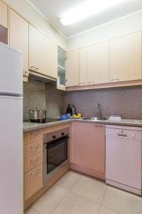 a kitchen with wooden cabinets and a white refrigerator at Pierre & Vacances Andorra El Tarter in El Tarter