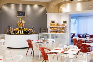 a restaurant with white tables and chairs and a bakery at Aparthotel Los Dragos del Sur in Puerto de Santiago