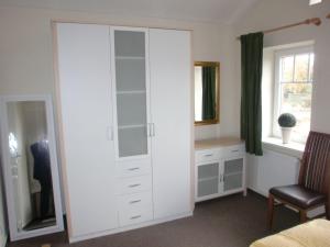 - une chambre avec un grand placard blanc et un bureau dans l'établissement Ferienhaus-Utspann, à Lemkenhafen auf Fehmarn