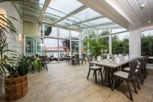 Un comedor con mesas y sillas y grandes ventanales. en Hotel Linderhof, en Erfurt