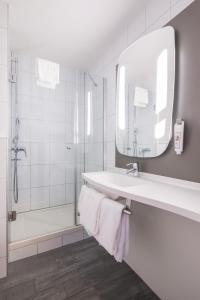 a bathroom with a shower, sink, and mirror at ibis Zürich Messe Airport in Zurich