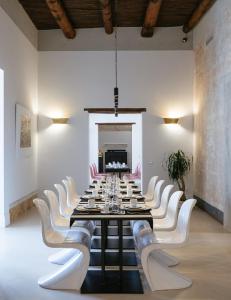 una grande sala da pranzo con un lungo tavolo e sedie bianche di Artemisia Domus - Centro Storico a Napoli