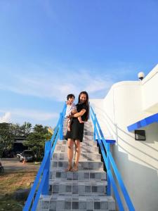 una mujer sosteniendo a un niño de pie en las escaleras en Fufu In Love en Khao Kho