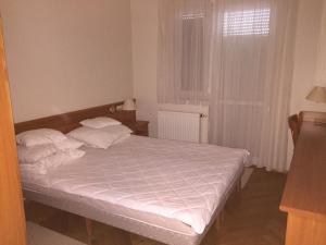 1 dormitorio con 1 cama con sábanas blancas y ventana en Vízközeli panorámás 4 fős apartman Badacsonytomajon, en Badacsonytomaj