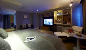 a living room with a large bed and a tv at Malmaison London in London
