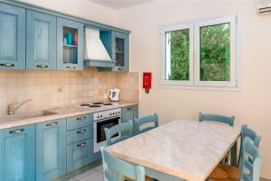 a kitchen with blue cabinets and a table with chairs at Olivia Villa in Kolymbia