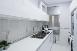 a white kitchen with a sink and a refrigerator at New Apartment Retiro Park 6pax in Madrid