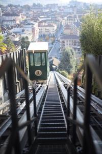 a green train on a bridge over a city at Albergo e Ostello della gioventù Biella centro storico in Biella