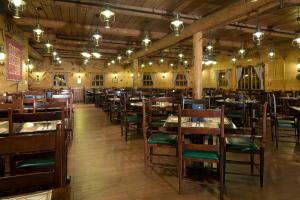un restaurante con mesas de madera, sillas y luces en Disney Davy Crockett Ranch, en Villeneuve-le-Comte