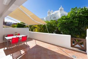 Luxury Bungalow In Costa Adeje في بلايا بارايسو: شرفة مع كراسي حمراء وطاولة مع مظلة