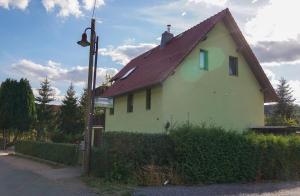 a yellow house with a brown roof on a street at Ferienwohnung in der Telle in Schmalkalden