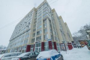 トムスクにあるБольшая Подгорная 57 квартира-студия с утепленной лоджиейの雪に車を停めた大きな建物