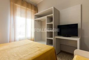 1 dormitorio con 1 cama, TV y ventana en Hotel Antonella, en Lido di Classe