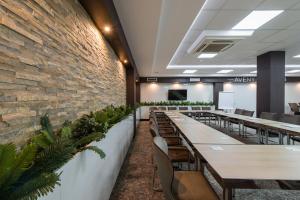 a dining room with tables and chairs and a brick wall at Garni Hotel Aveny in Čačak