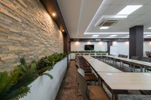 Garni Hotel Aveny في تشاتشاك: غرفة طعام مع طاولات وكراسي وجدار من الطوب