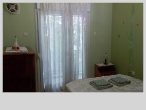 a bedroom with a bed and a window with white curtains at G & G guesthouse in Edessa