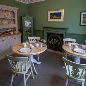 a kitchen with two tables and chairs and a fireplace at Garden House in Masham