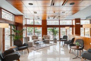 una sala de espera con sillas, mesas y ventanas en Hotel Dom Carlos Liberty, en Lisboa